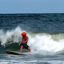 Kyle Talbott surfing in orange hat and camo shorts